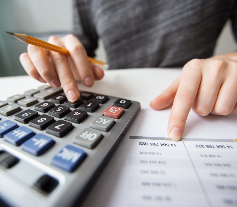 Closeup of accountant counting on calculator and working with table